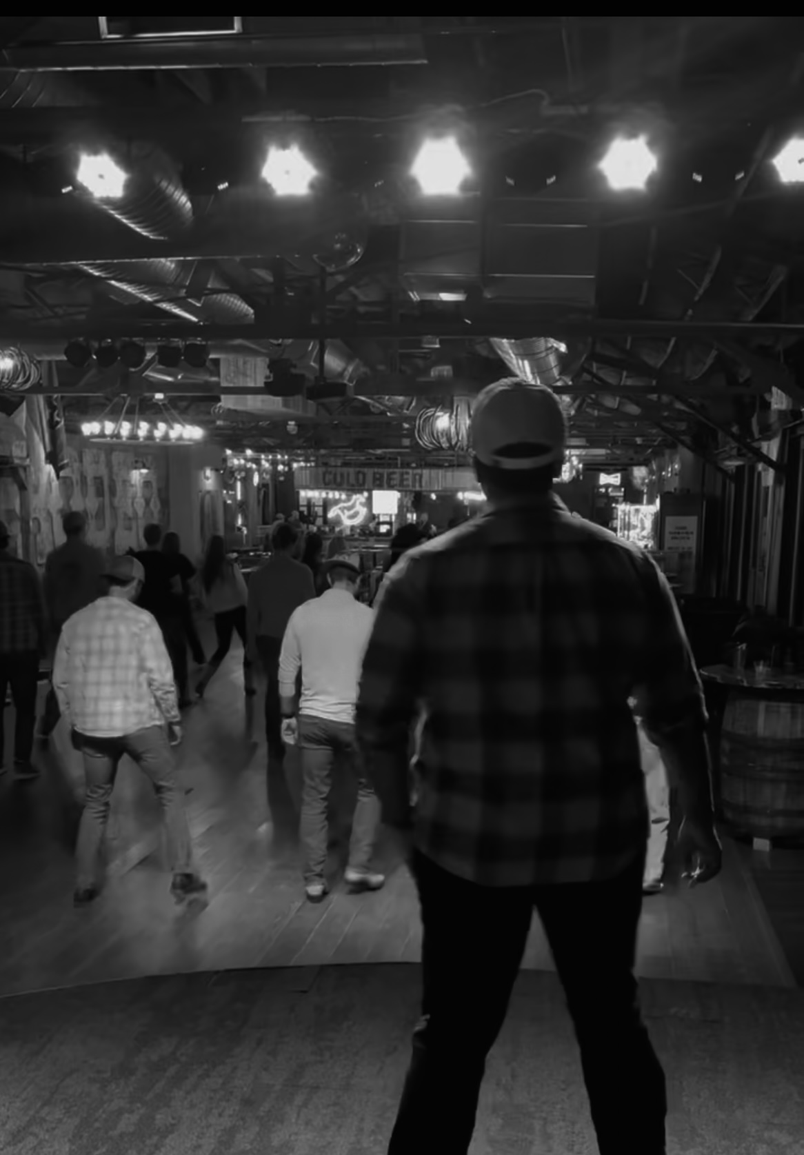 A public line dance lesson, viewed from behind the instructor facing the dancers